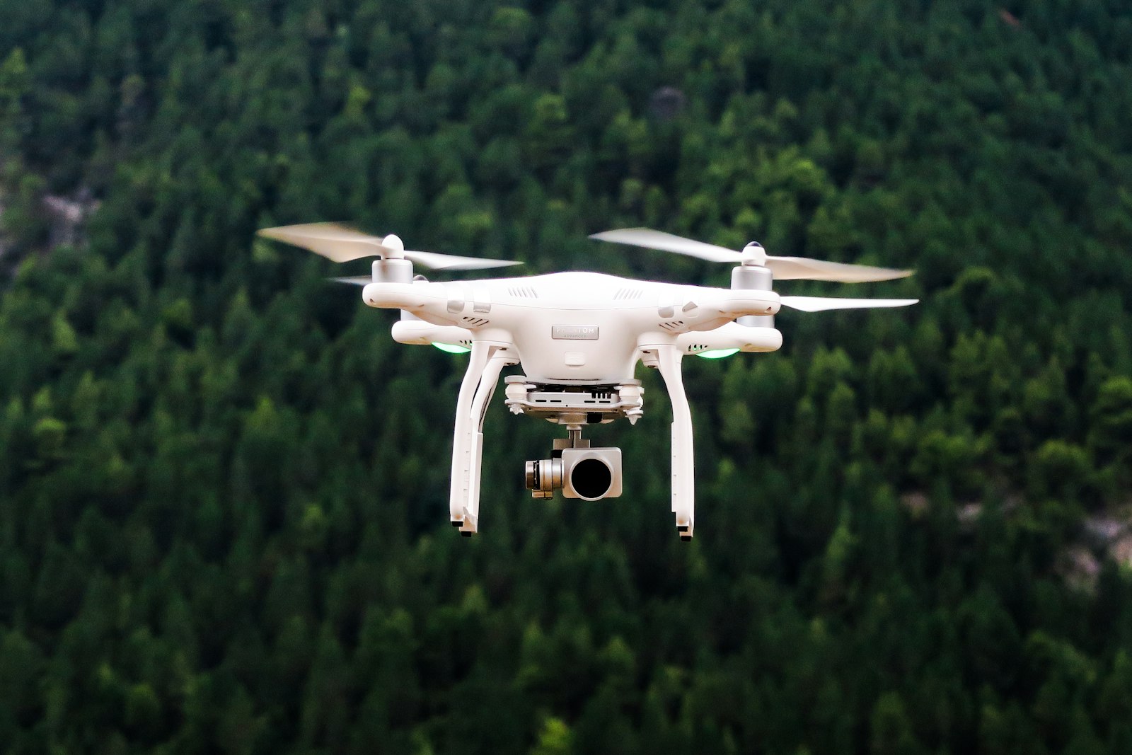 A camera drone hovering in front of a forested hillside, the aerial viewpoint drones open up for a learner group.