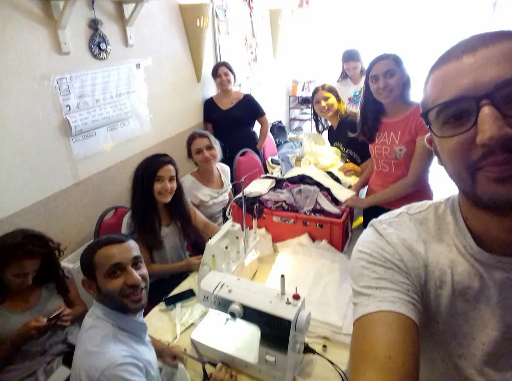 Volunteers gathered around a sewing machine during a hands-on upcycling workshop at the EVEC office in Kocani.