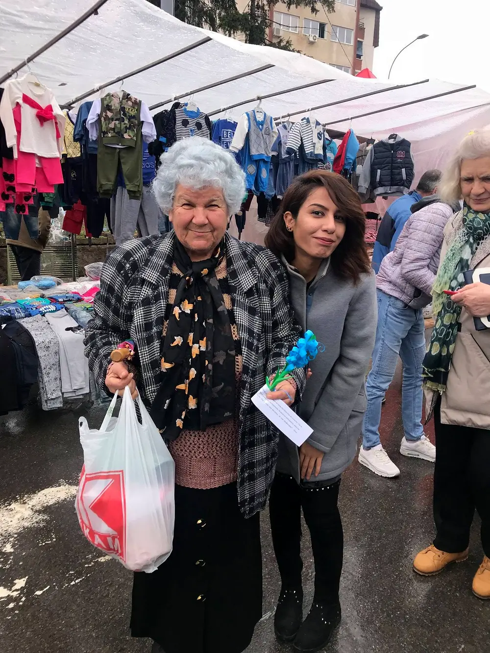 An EVEC volunteer standing with an older resident at a market in Kocani.