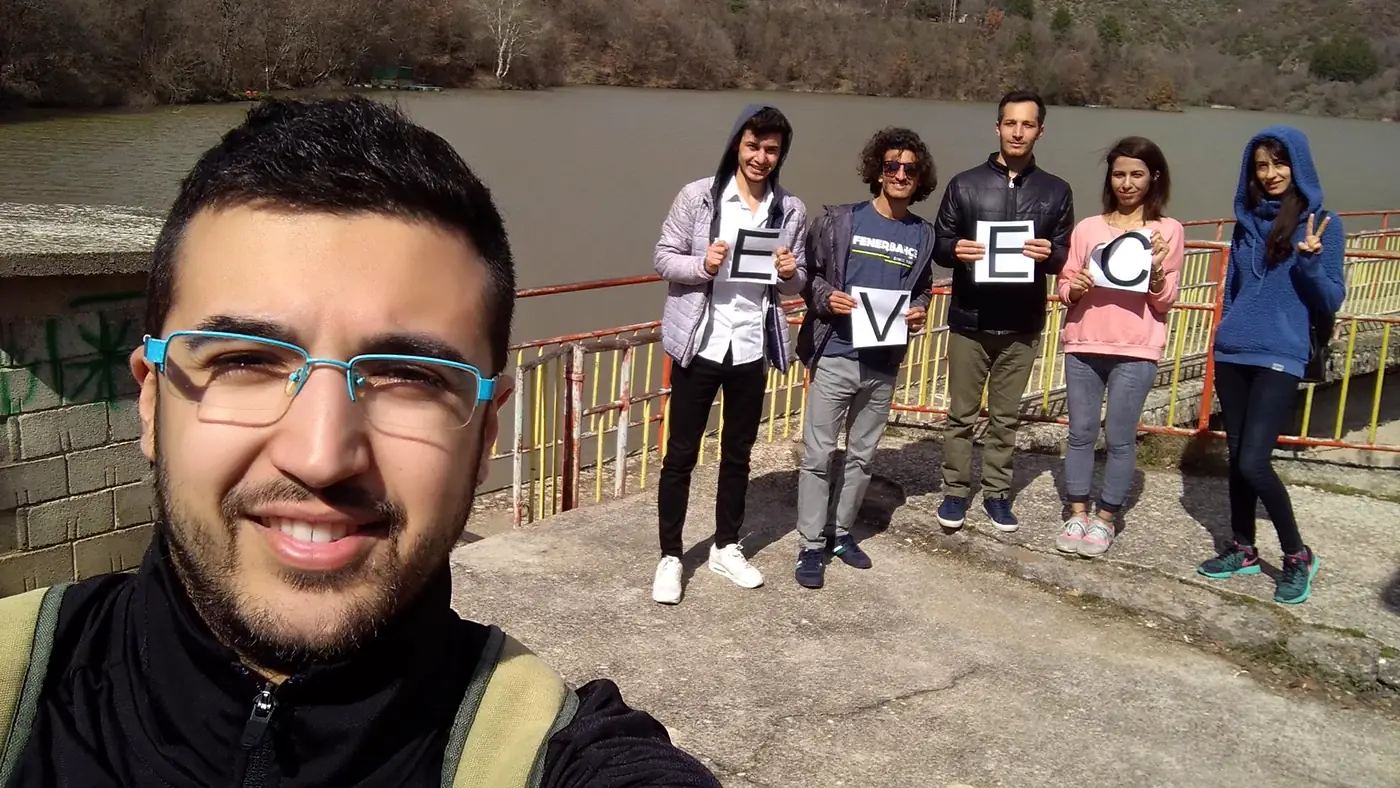 EVEC volunteers standing on a walkway above the water holding letters that spell EVEC