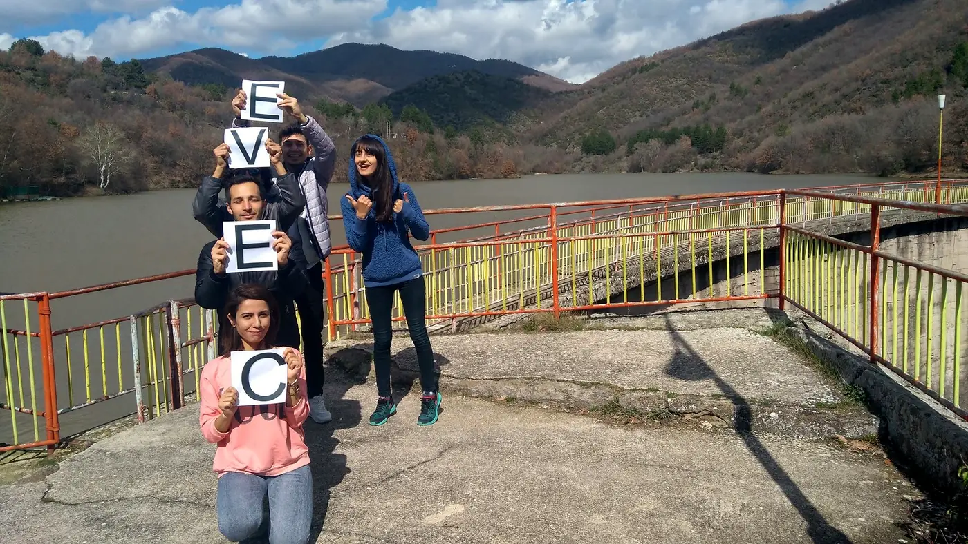 EVEC volunteers holding letters that spell EVEC at a viewpoint over a lake and hills